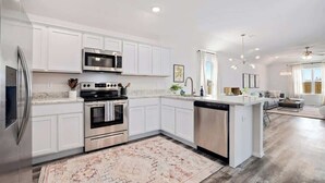 Una cocina moderna con muebles blancos, electrodomésticos de acero inoxidable y una isla central.
