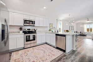 A modern kitchen with white cabinetry, stainless steel appliances, and a central island.