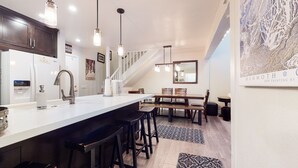 A modern kitchen with a white island, dark bar stools, a stainless steel faucet, and pendant lighting. - Bright Unit, Quiet Location, Near Mountain Bike Trails, Balcony. On-site Pool (Mammoth Lakes)