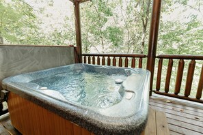 Relax in a hot tub on a raised deck surrounded by lush greenery.