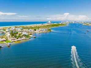 An aerial view of a coastal area with a marina, buildings, and a bridge in the distance.