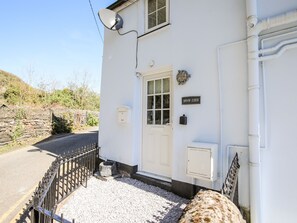A white building with a black door, a satellite dish, and a sign reading "BRYN COED".
