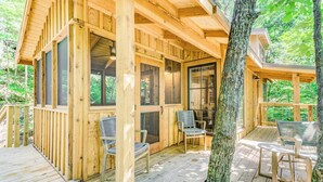 Uma cabana de madeira com varanda, janelas amplas e área de estar externa.