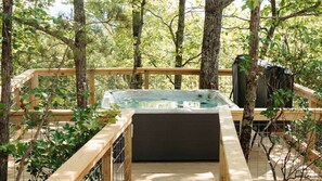 Un bain à remous sur une terrasse en bois, entouré d’arbres.