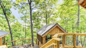 Eine Holzhütte mit einer Terrasse und einer kleinen Veranda, umgeben von Bäumen.