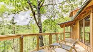 A wooden deck with two lounge chairs and a table, overlooking a forested area. - Outdoor Shower Treehouse in Smokies | Cottonwood (Sevierville)