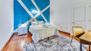 A bedroom with a bed, bedside tables, a chair, and a door. - Sosuite | 2BR Apt w W/D, Gym, On-Site Restaurant (Philadelphia)