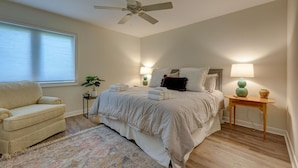A bedroom with a bed, a ceiling fan, a nightstand, a lamp, a chair, and a window with blinds. - 525 Plantation Club: Stylish Villa, 2 Bedrooms, Sleeps 6, Free Bikes, Pool (Hilton Head Island)