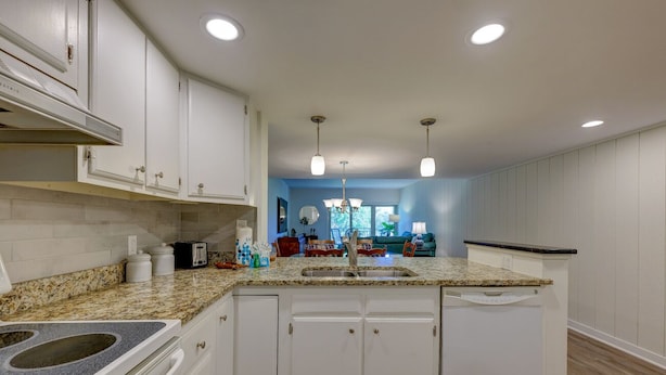 A kitchen with white cabinets, granite countertops, and a central island with a sink. - 525 Plantation Club: Stylish Villa, 2 Bedrooms, Sleeps 6, Free Bikes, Pool (Hilton Head Island)