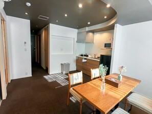 A modern kitchen with a microwave, stove, and sink. There is a dining area with a wooden table and chairs. - Two bedroom apartment - Two Bedroom Apartment / Osaka Ōsaka (Osaka)