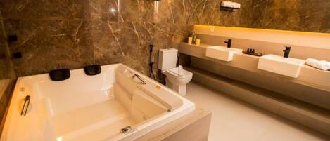 A modern bathroom with a large bathtub, a toilet, and a vanity with multiple sinks.