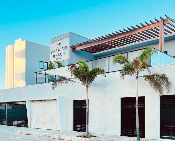 Stunning beachfront hotel with a modern design, flat roof, and pergola structure.
