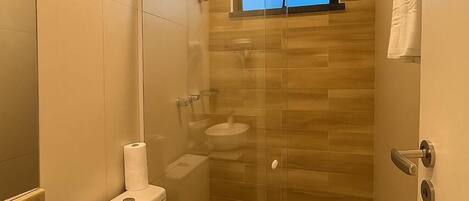 Un baño moderno con ducha vidriada, inodoro y lavamanos.