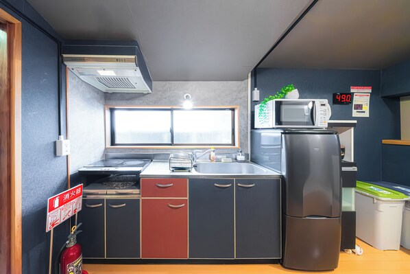 A compact kitchen with a microwave, refrigerator, and a window above the sink.
