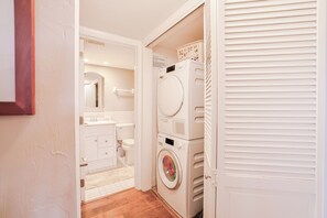 A compact laundry room with a washing machine, dryer, and stacked laundry baskets. - Tarpon Beach 112 offers the BEST Beach View! Stunning, Top Floor, Corner Unit (Sanibel)