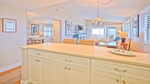 A kitchen with a large island, white cabinets, and a chandelier. - Tarpon Beach 112 offers the BEST Beach View! Stunning, Top Floor, Corner Unit (Sanibel)