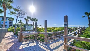 A wooden boardwalk leading to a beach with palm trees and a clear sky. - Tarpon Beach 112 offers the BEST Beach View! Stunning, Top Floor, Corner Unit (Sanibel)