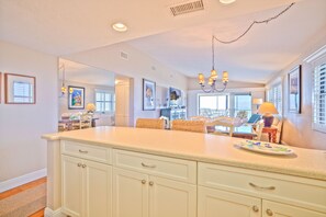 A kitchen with a large island, white cabinets, and a chandelier. - Tarpon Beach 112 offers the BEST Beach View! Stunning, Top Floor, Corner Unit (Sanibel)