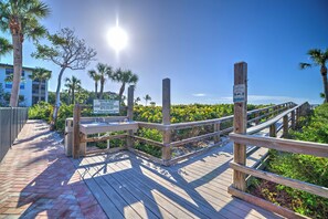 A wooden boardwalk leading to a beach with palm trees and a clear sky. - Tarpon Beach 112 offers the BEST Beach View! Stunning, Top Floor, Corner Unit (Sanibel)