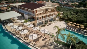Un hotel con piscina, tumbonas, sombrillas y vistas del entorno.