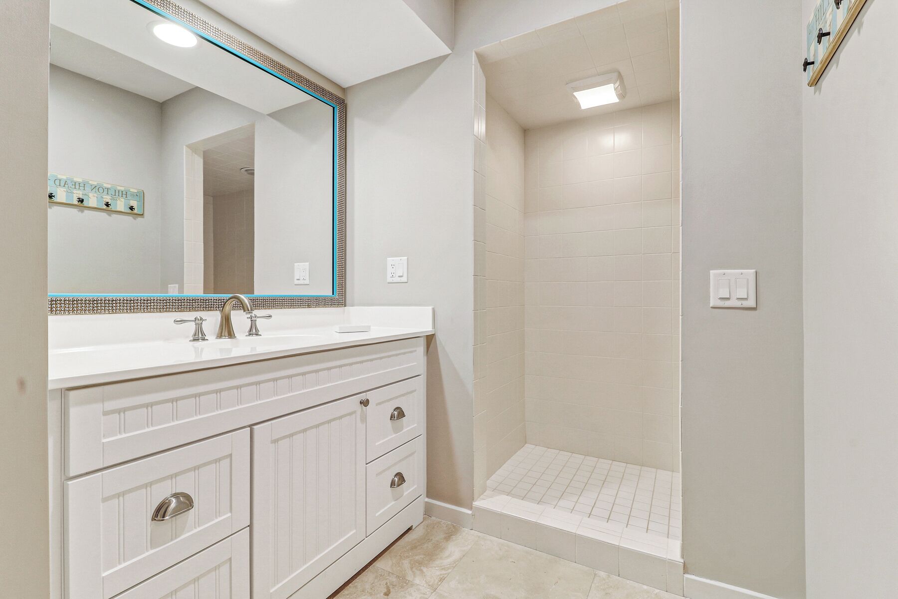 A bathroom with a white vanity, a large mirror, and a walk-in shower.