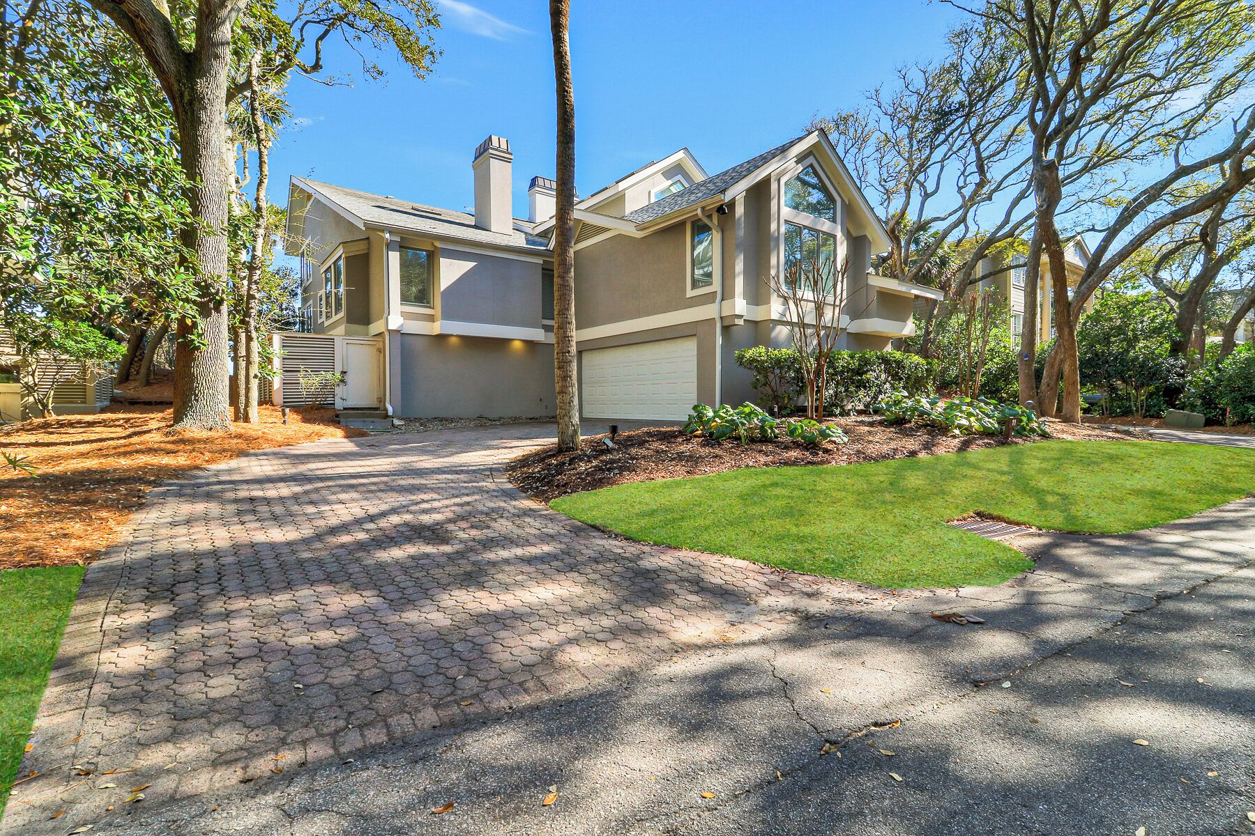 A modern two-story house with a paved driveway, a well-maintained lawn, and mature trees.