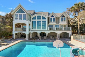 Une grande maison à deux étages avec une piscine à l’avant.