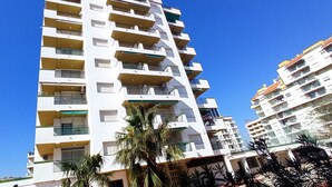 A multi-story residential building with balconies, a clear blue sky, and palm trees in the foreground. - Peñíscola Playa Inmomart (Peñiscola)
