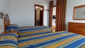 A hotel room with two beds, a wooden dresser, a mirror, and a door leading to a bathroom. - Peñíscola Playa Inmomart (Peñiscola)