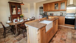Une cuisine dotée de meubles en bois, d’un plan de travail en granit et d’un coin repas avec une table dressée pour quatre personnes.