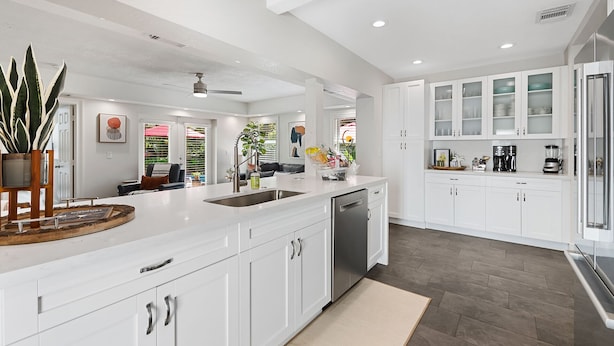 A modern kitchen with white cabinetry, a central island, and a built-in dishwasher. - Beautiful Tropical Retreat Near Fort Lauderdale Beach, Las Olas & Top Attractions (Fort Lauderdale)