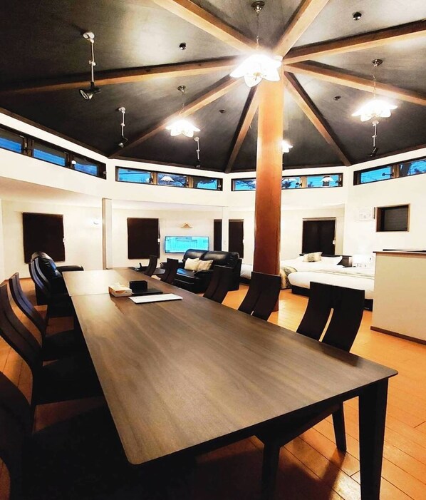 A spacious conference room with a long table, multiple chairs, and a large wooden pillar.