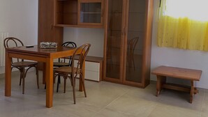 Een eetruimte met een houten tafel en stoelen, een kast met glazen deuren en een kleine bank.