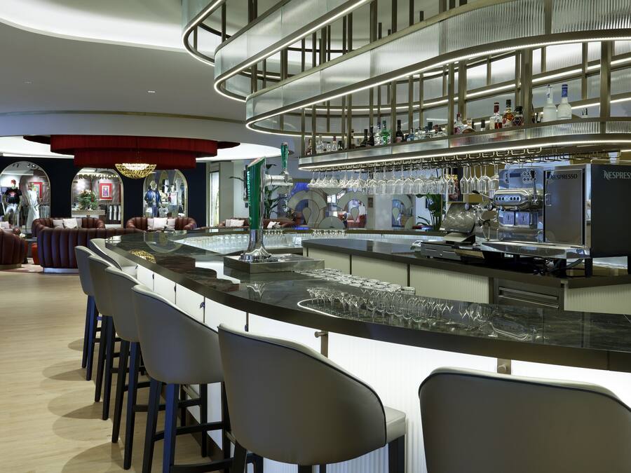 Una zona de bar moderna con una barra curva, taburetes y una máquina Nespresso.