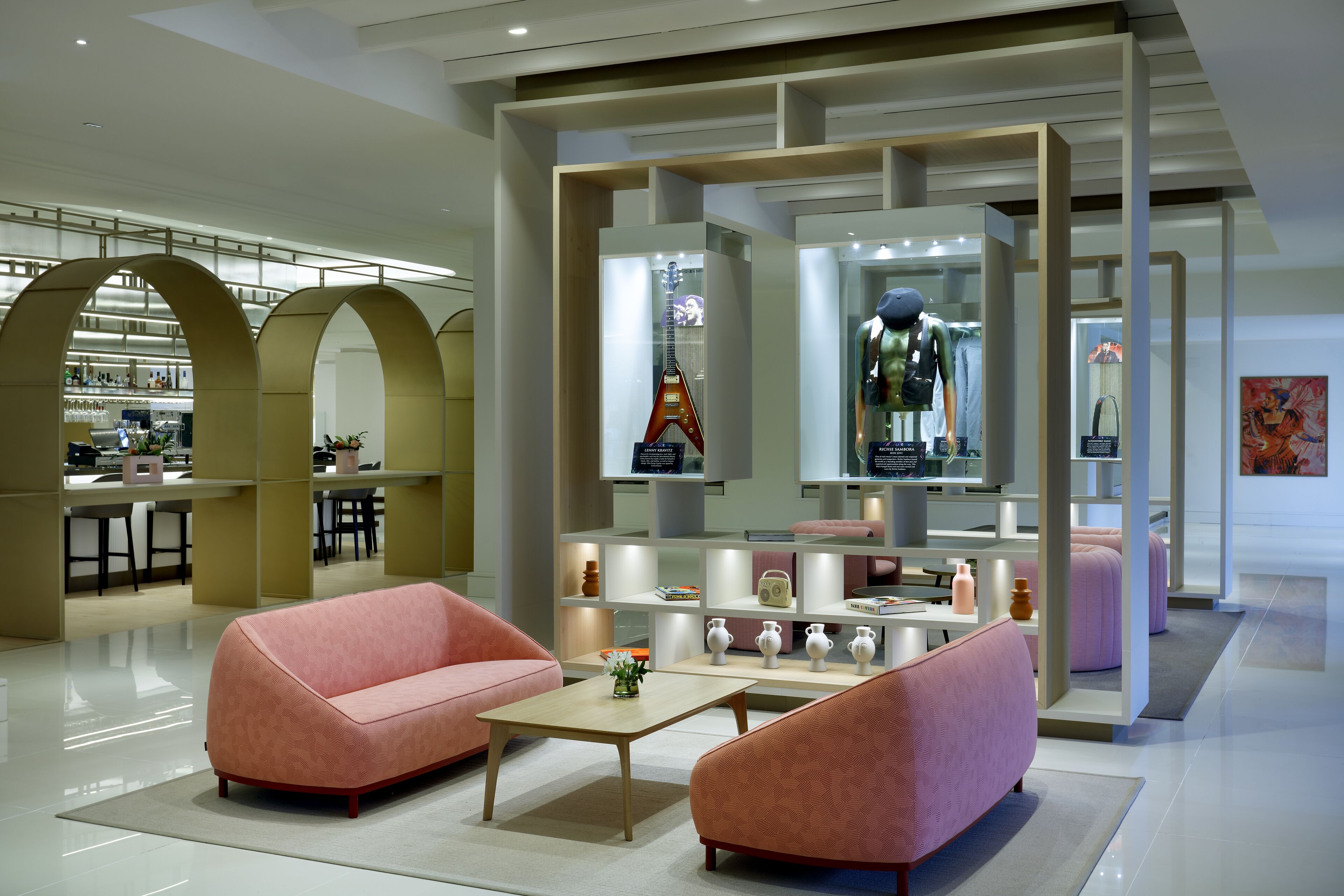 A modern interior with pink sofas, a coffee table, and a display of decorative items.