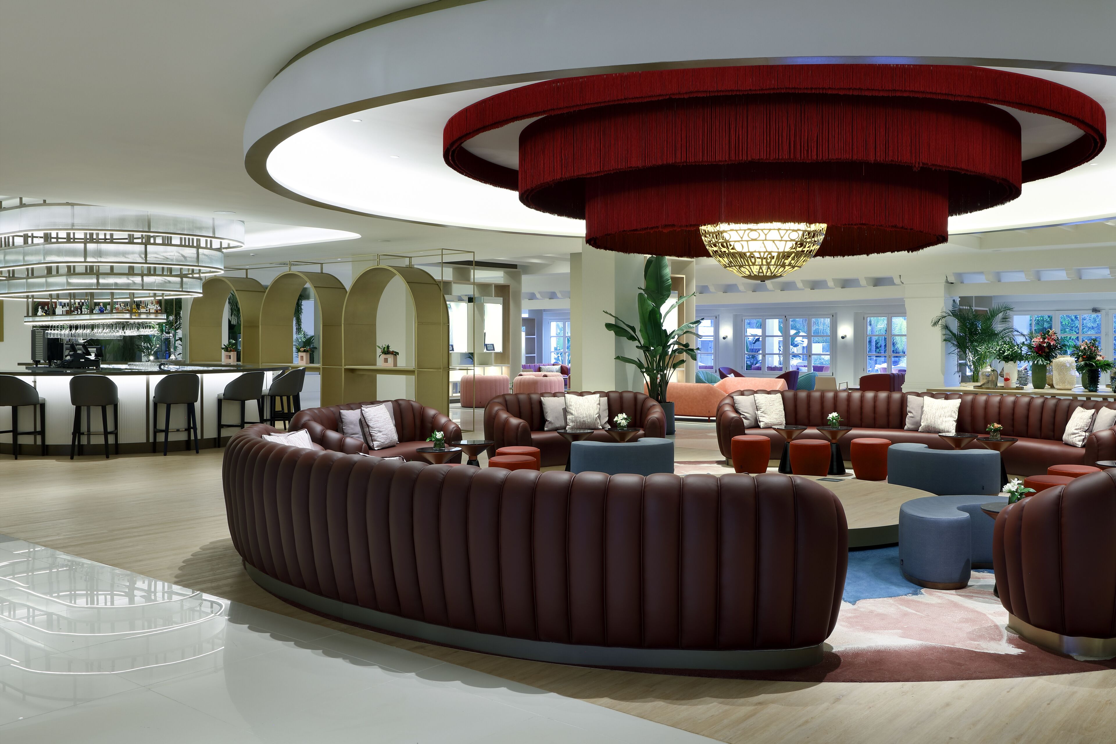 A modern lobby with a central seating area, a bar, and a staircase.