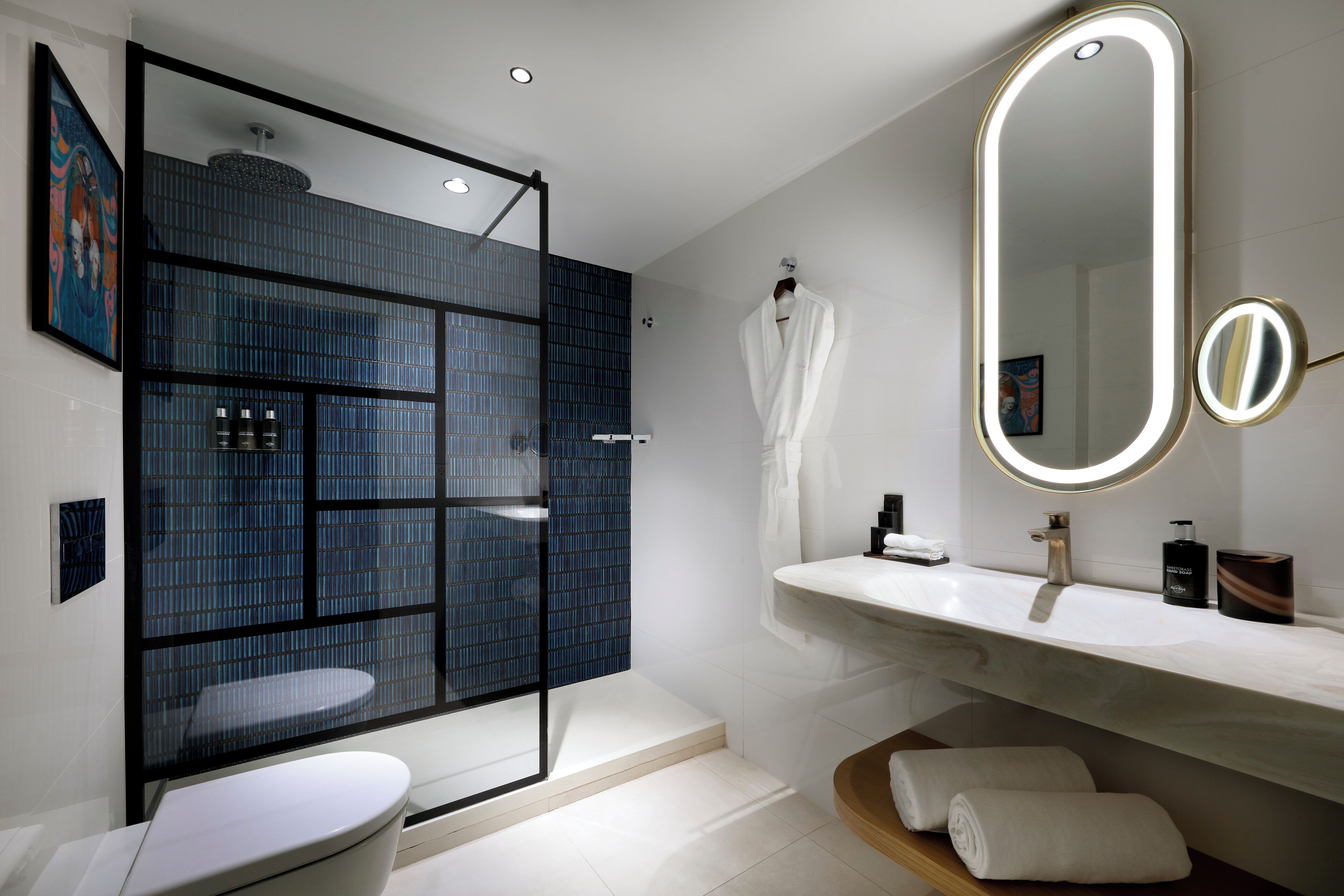 A modern bathroom with a glass-enclosed shower, a large mirror, and a white sink.