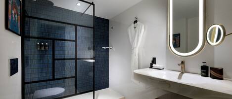 A modern bathroom with a glass-enclosed shower, a large mirror, and a white sink.