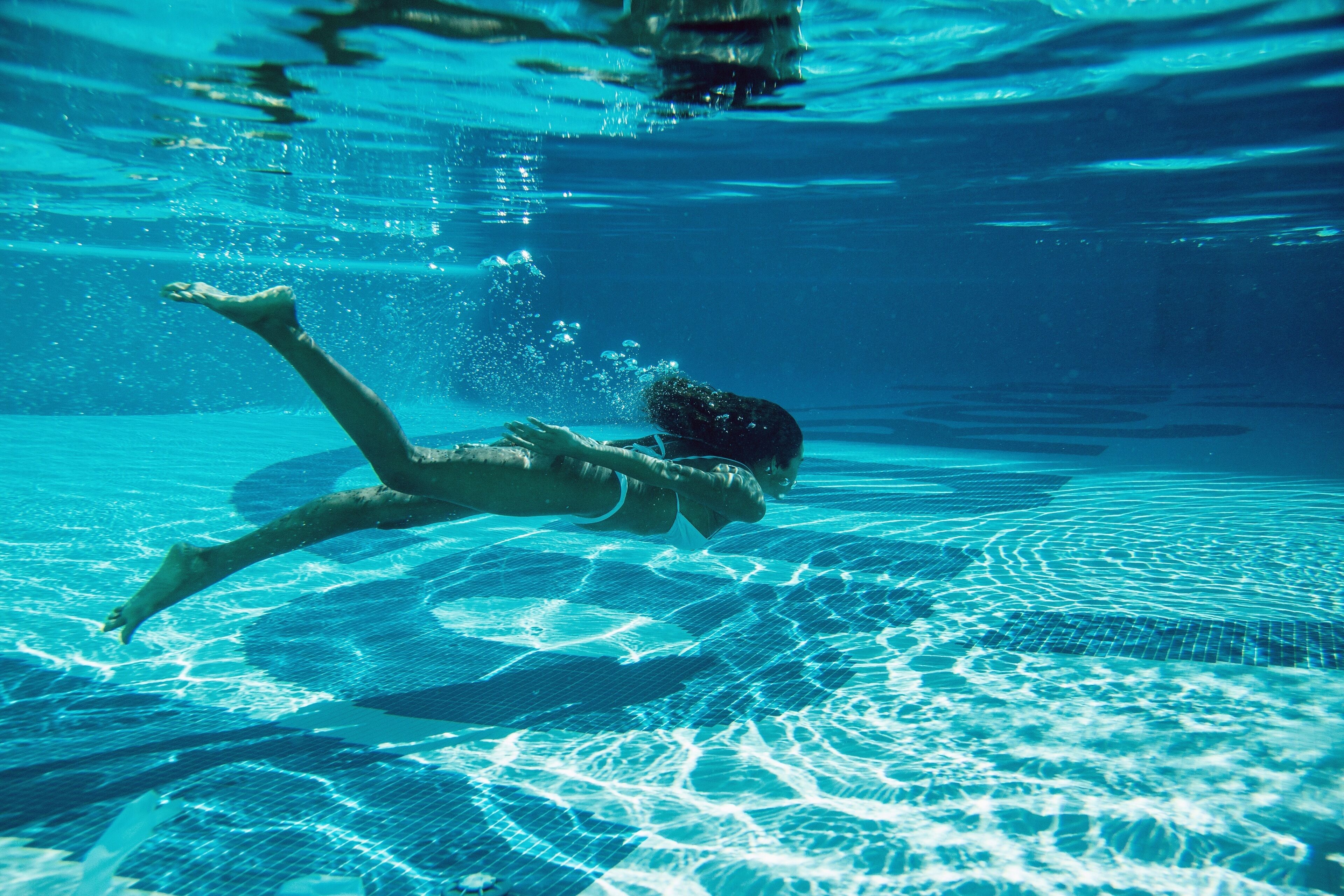 Eine Person schwimmt unter Wasser in einem Schwimmbecken.