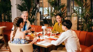 Un grupo de personas cenando en un restaurante con una decoración moderna, que ofrece diferentes tipos de asientos y un arreglo decorativo de plantas.
