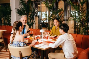 Een groep mensen dineert in een restaurant met een modern interieur, met een combinatie van zitplaatsen en een decoratieve plantenopstelling.