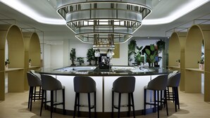 A modern bar area with a circular bar, four bar stools, and a central chandelier. - Hard Rock Hotel Marbella – Puerto Banús (Marbella)