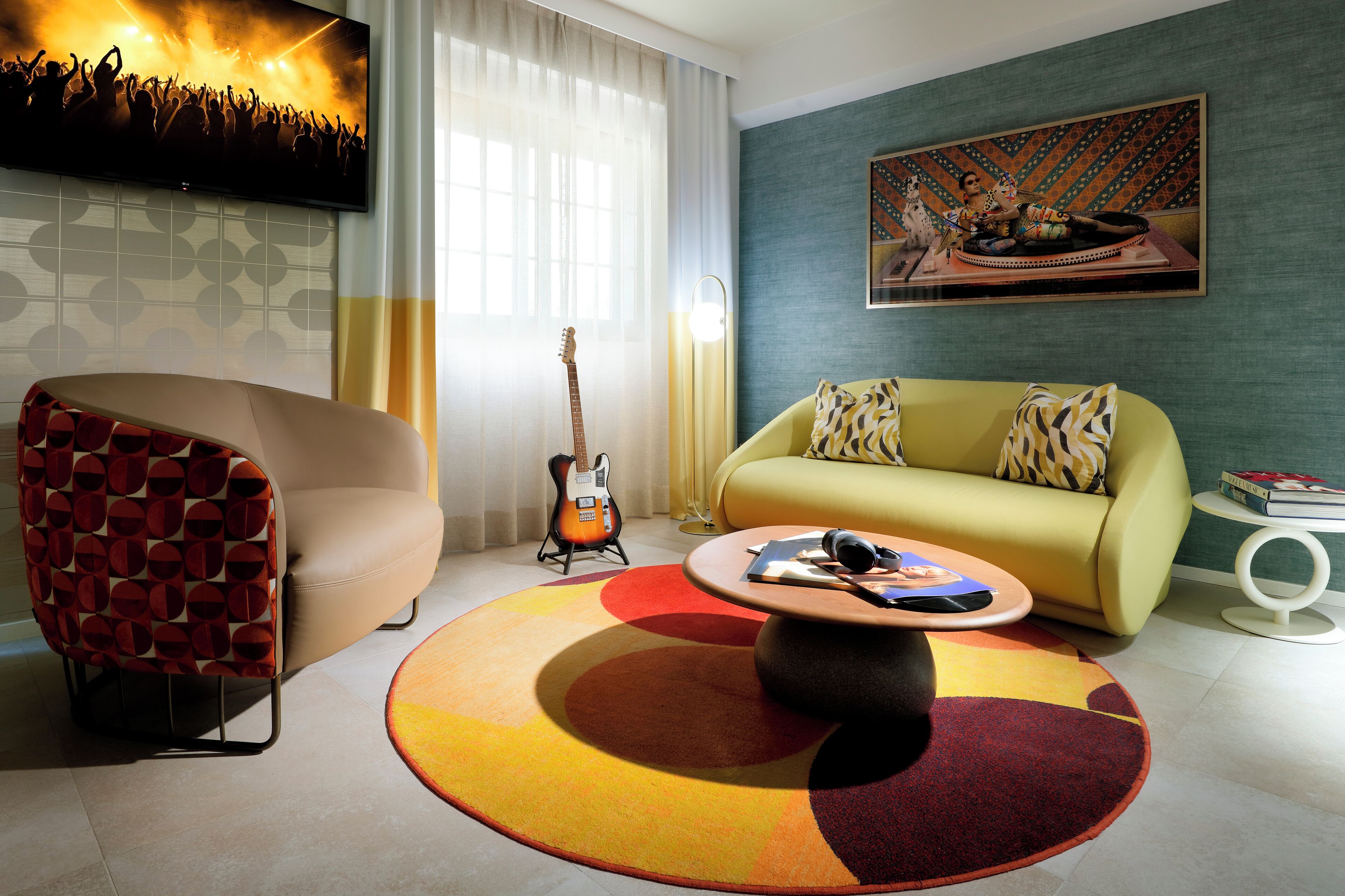 Una sala moderna con un sofá, un sillón, una mesa de centro y una guitarra.