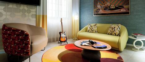 A modern living room with a sofa, a chair, a coffee table, and a guitar.