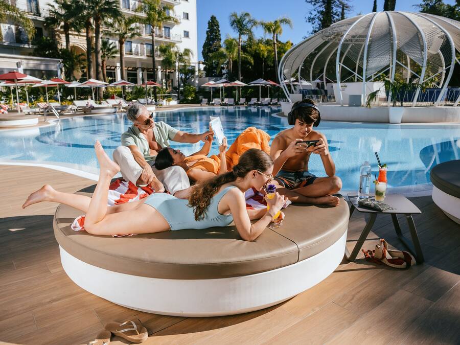 Un espace de détente au bord de la piscine, avec des sièges disposés en cercle, une petite table avec une boisson, et une piscine en arrière-plan.
