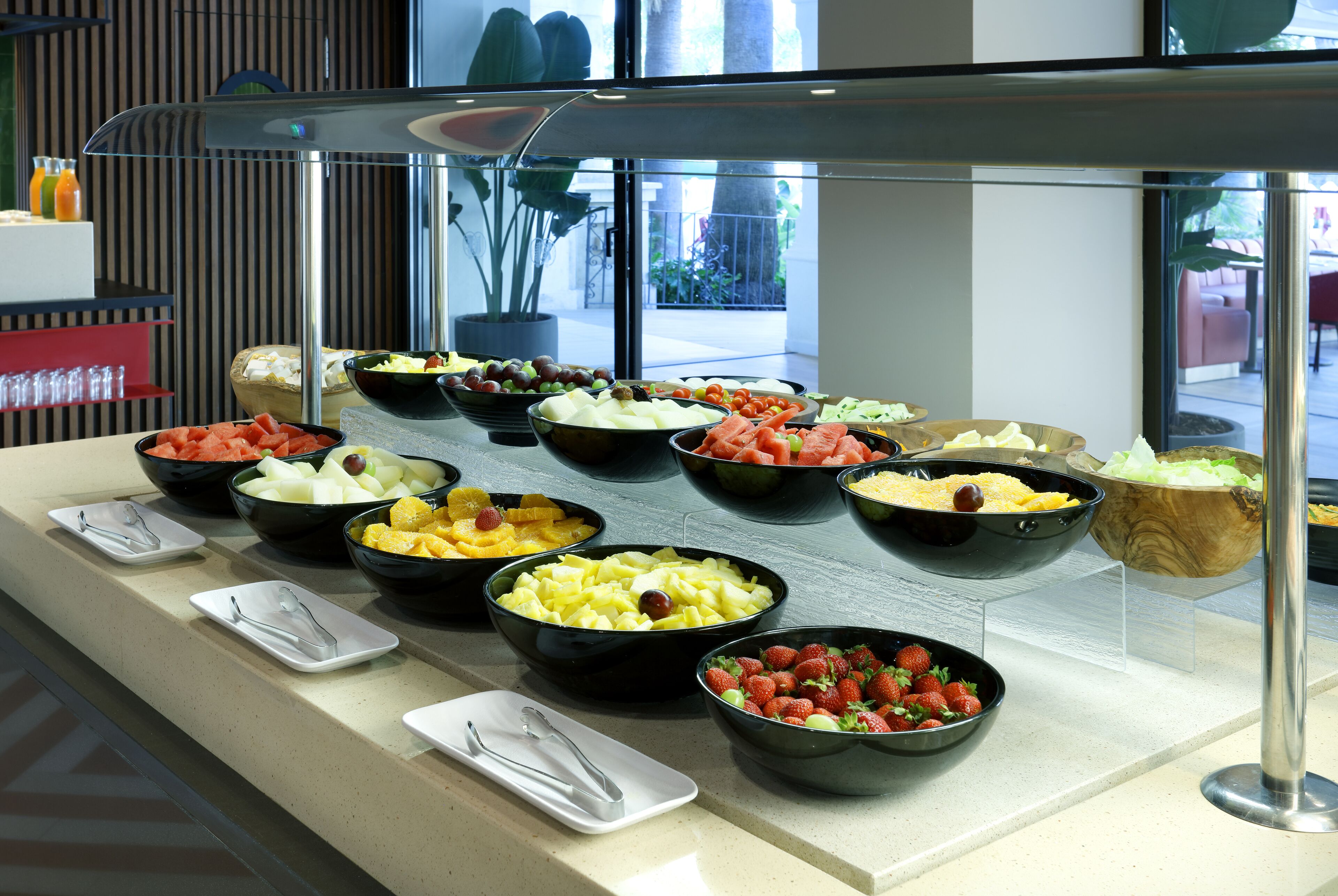 A buffet with various fruits and vegetables arranged on a counter.