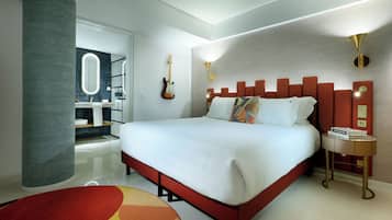 Ein modernes Hotelzimmer mit einem großen Bett, einem Badezimmer mit Spiegel und einer Gitarre an der Wand.