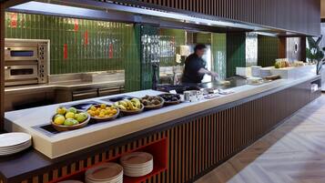 A buffet setup with multiple food stations, including a fruit bowl and a variety of dishes.