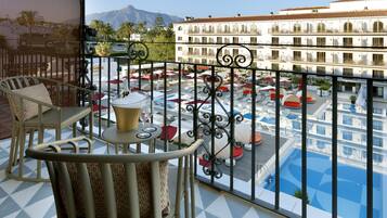A balcony with a pool view, outdoor seating, and a building in the background.