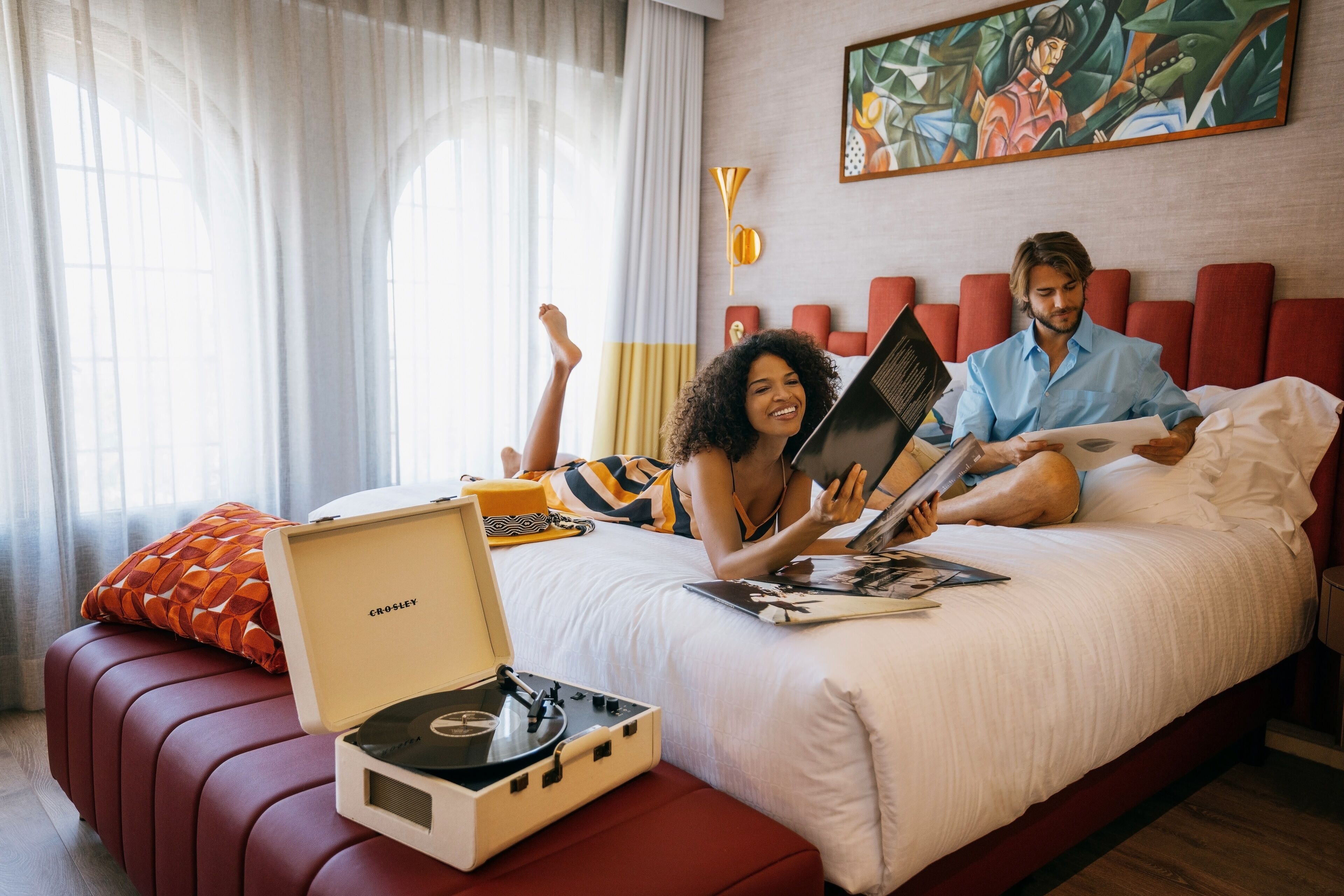 Ein Schlafzimmer mit einem Bett, einem roten Sofa, einem Plattenspieler und einem Laptop.